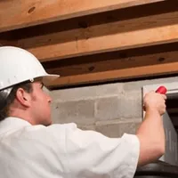 Termite inspection technician checking a basement wall and framing for termite activity in Henderson, NV